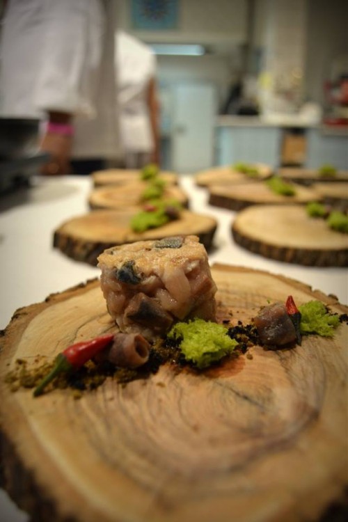 L’ulivo incontra il mare, sgombro marinato e poi scottato, servito con polvere di olive celline su di un piatto di legno d’ulivo