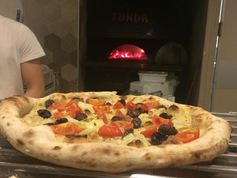 Tonda, pizza in uscita dal forno a legna