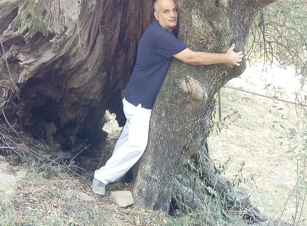 Carlo Sacchi mentre abbraccia l'albero di ulivo ultramillenario