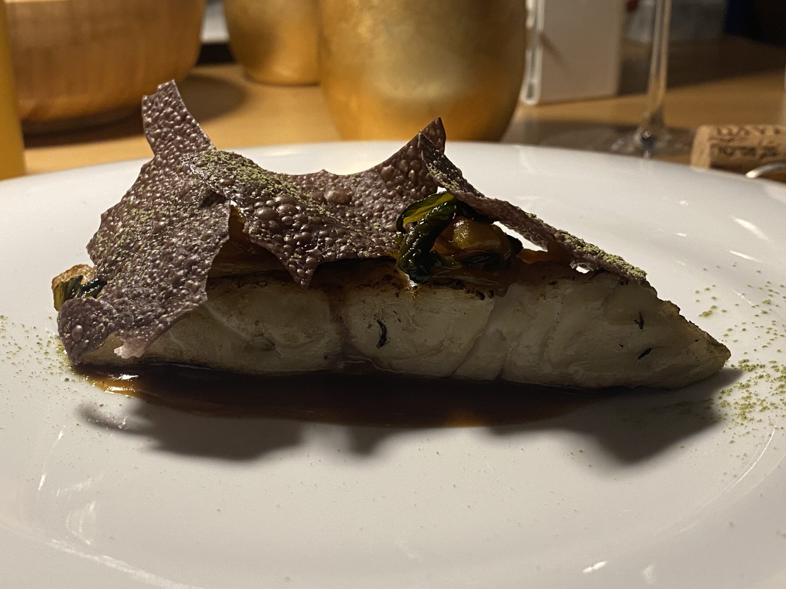 Spigola-Warayaki-Spigola-cotta-con-il-fuoco-del-fieno-accompagnata-con-Jus-di-pollo-chips-di-olive-nere-e-pak-choy-marinato-in-miso-rosso