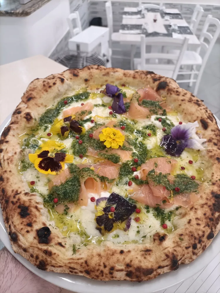 SORRENTINO - La pizza Sorrentino con fior di latte, salmone affumicato, stracciatella di bufala, pesto di rucola, zeste di limone, pepe rosa e fiori