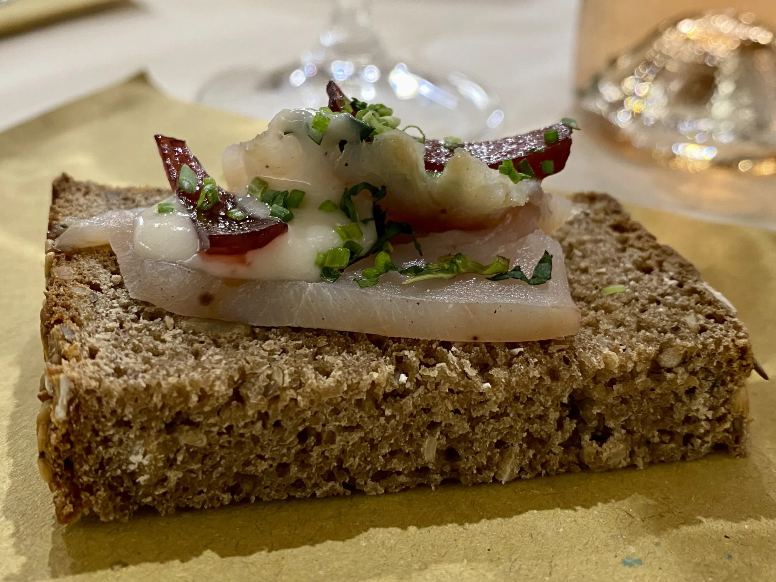 Pane-di-segale-il-rugbrod-dane-se-con-hummus-di-fagioli-cipolle-caramellate-lamponi-carpacc-io-di-ricciola-timo-e-salvia-