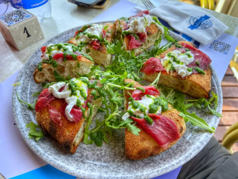 La pizza al padellino. Carpaccio di black Angus affumicato, rucola, fonduta di parmigiano e feste di limone