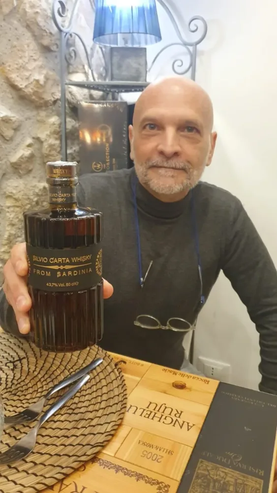 Pino Perrone con la bottiglia di Whisky di Silvio Carta