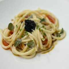 Spaghetto alla chitarra, estrazione e garum di croste di parmigiano, pomodoro in papillote e cipolle di Acquaviva: la ricetta di Giuseppe Amato